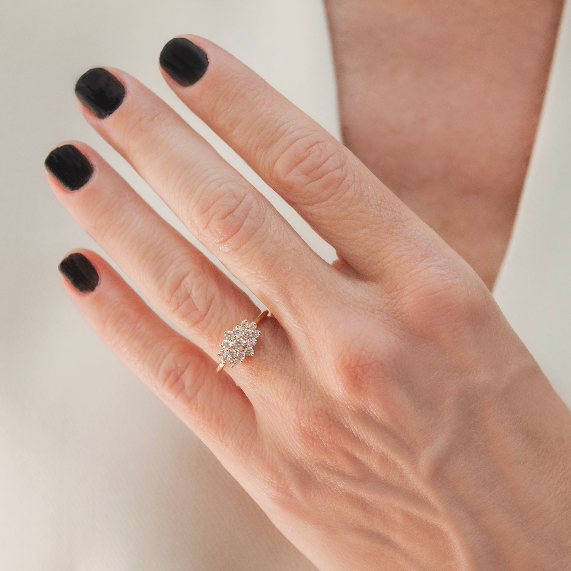 Anillo de oro 18K con rosetón de diamantes en una mano