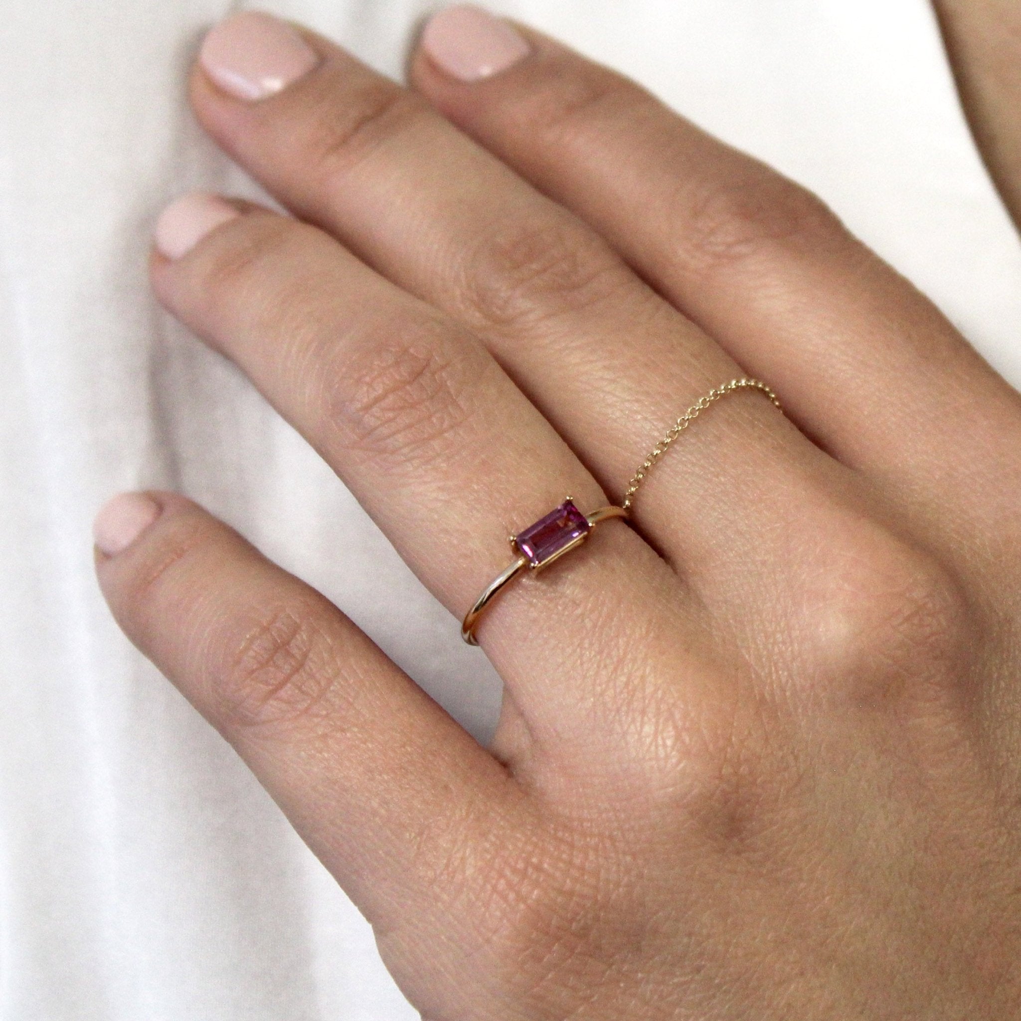 Anillo de oro 18K con rodolita talla baguette en la mano de una mujer