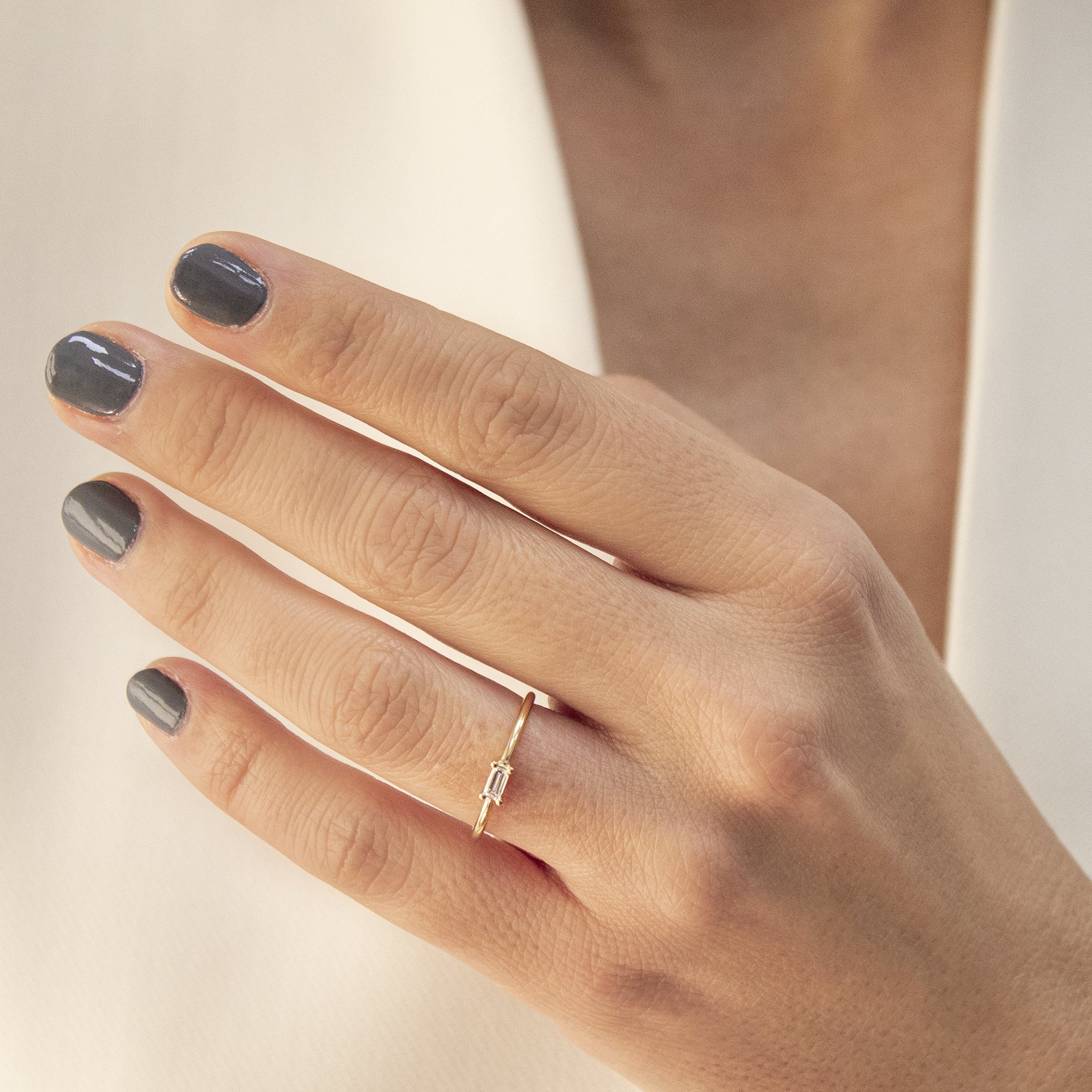 Anillo solitario oro 18K y diamante talla Baguette en el dedo de una mujer