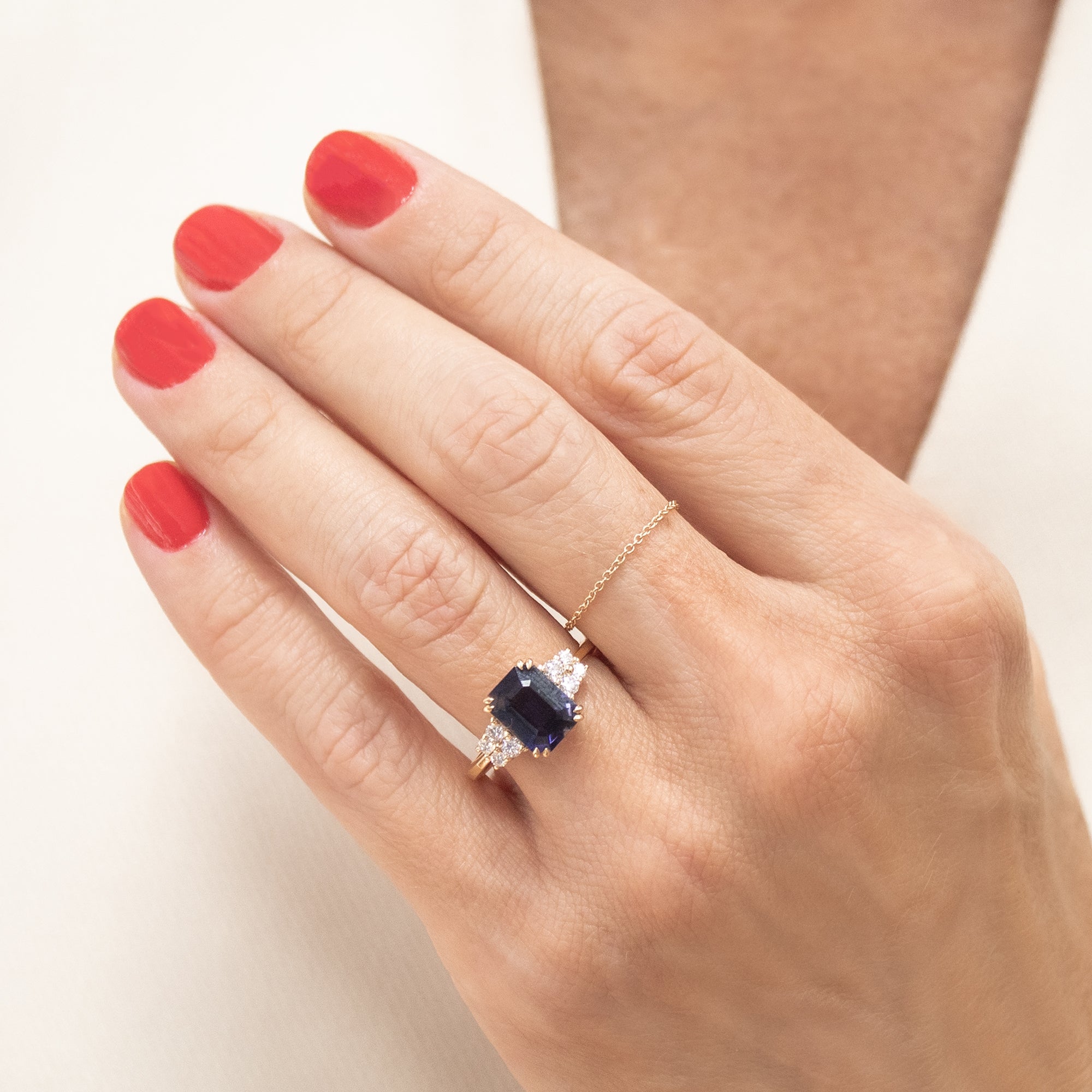 Anillo oro 18K con piedra lolita central y diamantes en la mano de una mujer