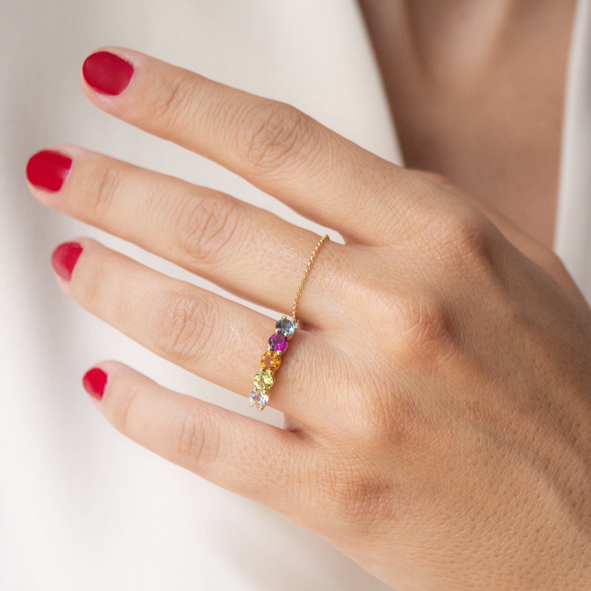 Anillo cinquillo oro 18K con piedras preciosas en el dedo de una mujer