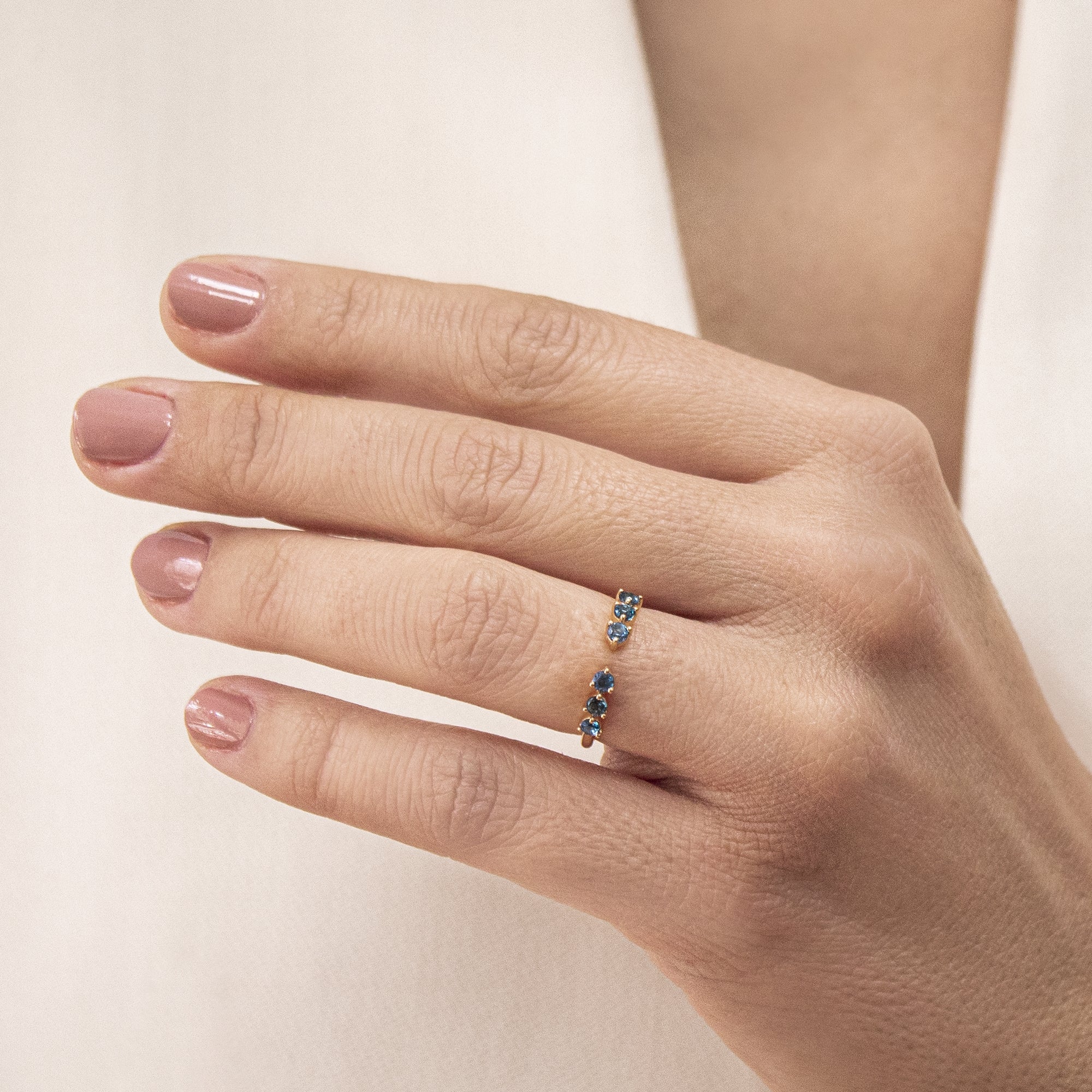 Anillo abierto en oro 18k con topacios en azul en mano