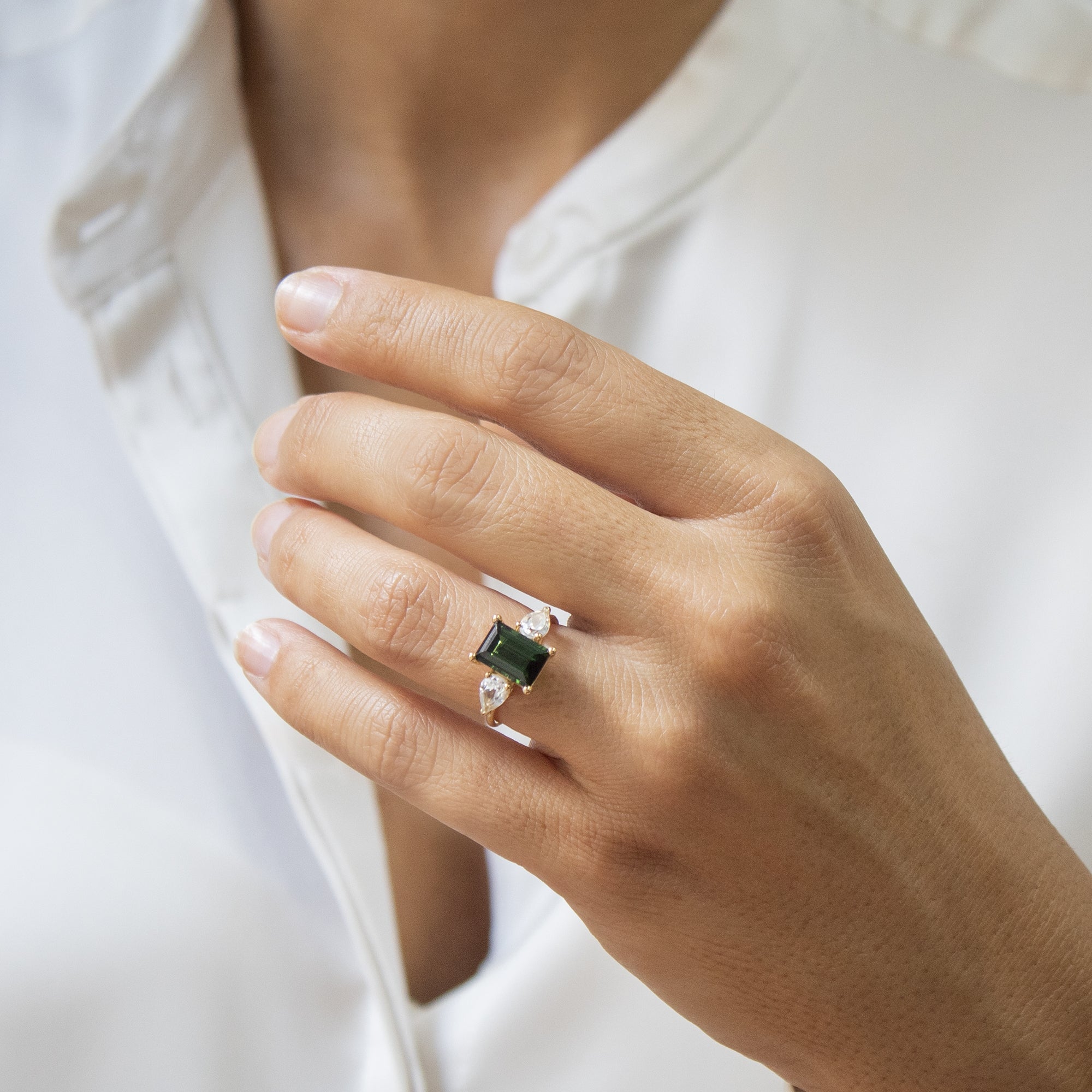 Anillo trilogía  en oro 18K de topacio, diamantes y turmalina en el dedo de una mujer