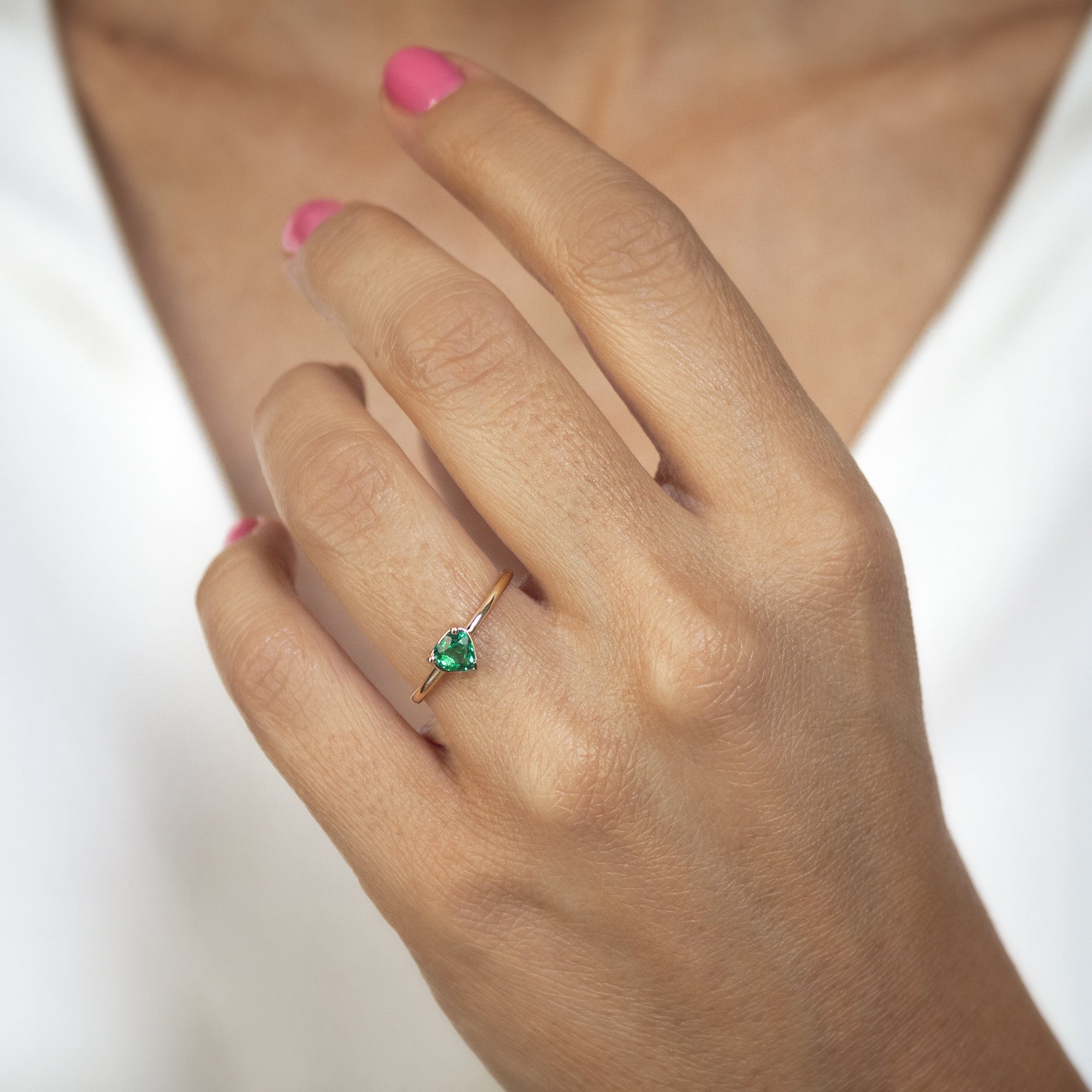 Anillo en oro 18K y esmeralda talla corazón en la mano de una mujer